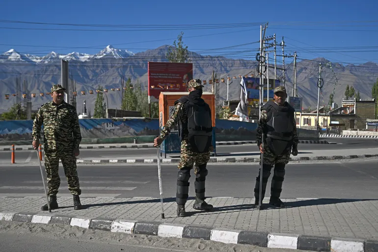 Security personnel stand guard along a road during a curfew in Leh on September 28, 2025