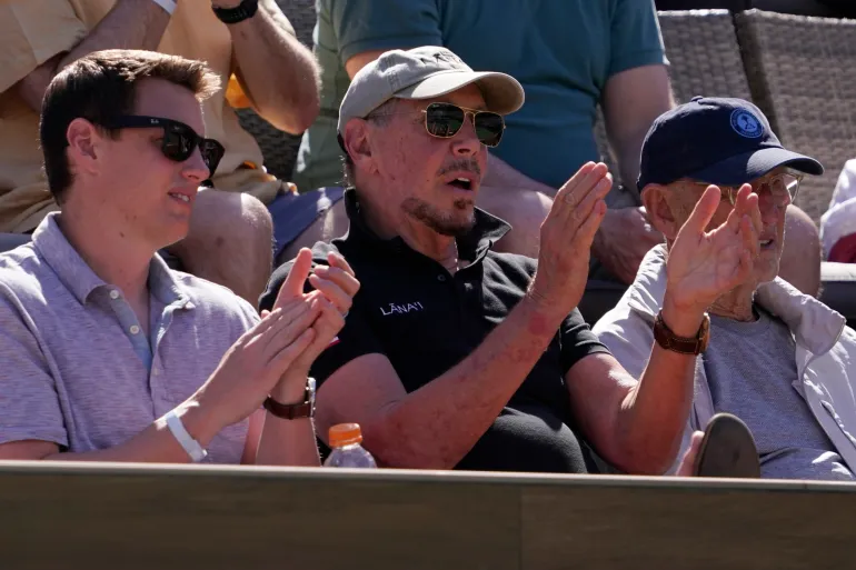 Larry Ellison, center, of Oracle, looks on as Rafael Nadal, of Spain, plays Daniel Evans, of Britain, at the BNP Paribas Open tennis tournament Monday, March 14, 2022, in Indian Wells, Calif. (AP Photo/Mark J. Terrill)